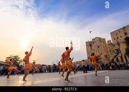 Aleppo, Aleppo Governorate, Syria : Men in traditional costumes dance by the citadel of Aleppo. Stock Photo