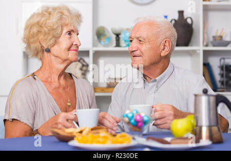 Portrait of happy mature couple having good time drinking tea in kitchen Stock Photo