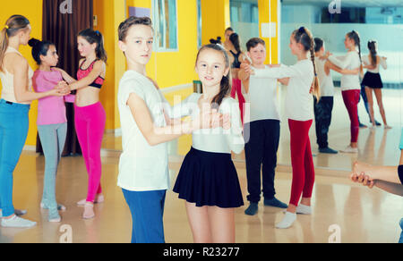 Group of tweens training movements of slow foxtrot in dance studio with female coach Stock Photo