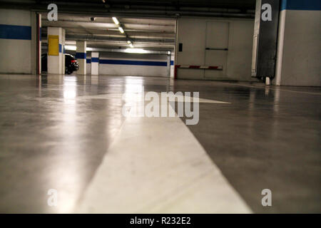 White arrow drawn on the ground in a parking / Old arrow street sign on road / Road traffic marking on street / Underground parking garage. Stock Photo