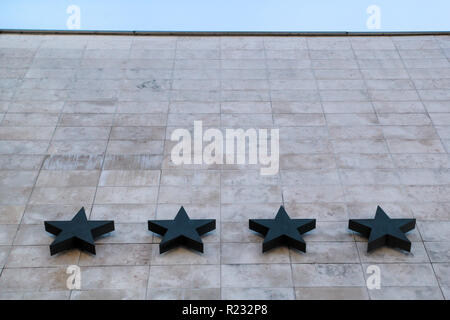 Hotel and hospitality / Four stars on the stone wall of the hotel / Quality of hotel and motel services / In the background of the blue sky. Stock Photo