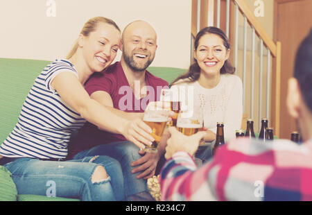 Cheerful laughing young adults drinking beer at home Stock Photo