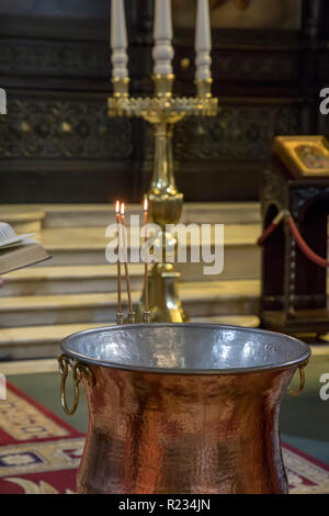 Christening in the church. Church utensils in the Orthodox church. A big bowl of water for the baptism of a baby with wax candles. Stock Photo