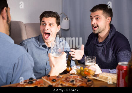 Friendly meeting in men company over beer with pizza at home Stock Photo