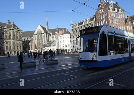 In Dam Square Amsterdam. In the distance is the Nieuwe Kerk is a 15th-century church, next to the Royal Palace. Formerly a Dutch Reformed Church parish, it now belongs to the Protestant Church in the Netherlands. In the foreground is a tram on the network. Stock Photo