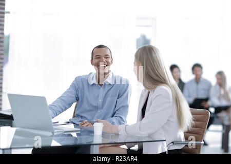 Beautiful young business partners are using a laptop, discussing documents Stock Photo