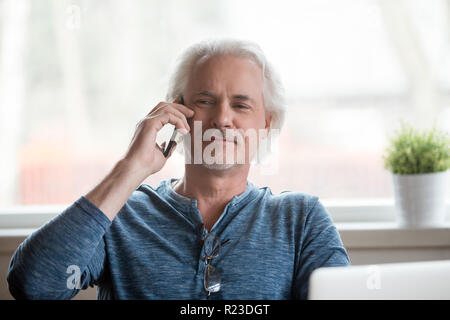 Proud senior man talking on cell phone having pleasant conversation at home, satisfied aged male happy speaking over smartphone relaxing in chair. Eld Stock Photo