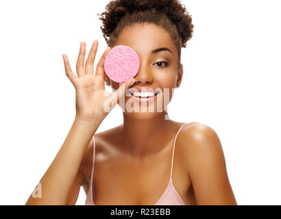 Funny girl holding pink sponge near her face. Portrait of young african american girl on white background. Youth and skin care concept Stock Photo