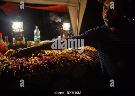 Zanzibari street vendor and chef show his snacks at night street food market in Forodhani Gardens. Stone Town, Zanzibar City, Unguja island, Tanzania. Stock Photo