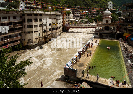 India, Himachal Pradesh, Manikaran, 08/15/2010: a public hot water pool along the Parvati river and, on the other side, the Gurudwara Shri Sahib Stock Photo