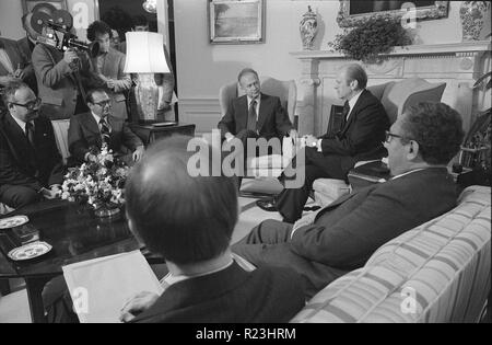President Gerald Ford sitting in chair in front of a fireplace, with Israeli Prime Minister Yitzhak Rabin and others including Henry Kissinger at the White House. 1976 Stock Photo
