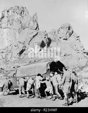 Ethiopian repatriation convoy. Ethiopian prisoners of war who are being released by the British are pushing one of the more than one hundred twenty trucks which transported them from a British internment camp in the Sudan to Dessye. In the background is Schafe Mountain. Stock Photo