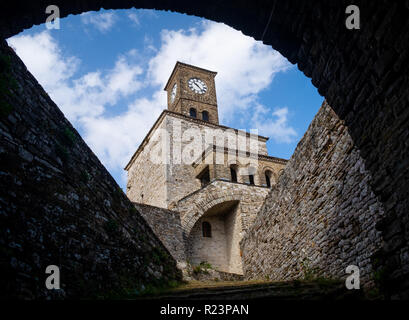 Framing through archway of the clock tower of the fortress of Gjirokaster in Albania, with a blue sky and white clouds background Stock Photo