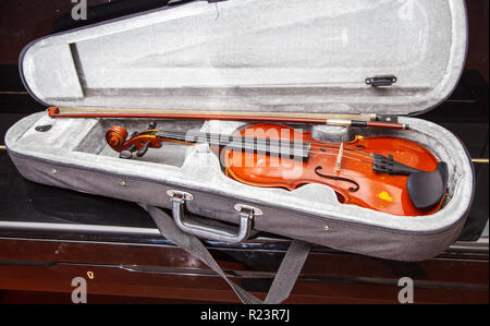 brown vintage violin with bow lying in a case indoor Stock Photo