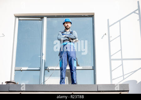 Portraiit of a builder in uniform standing on the balcony of a new house on the construction site Stock Photo