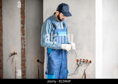 Electrician mounting wiring for electric sockets on the construction site of a new building indoors Stock Photo