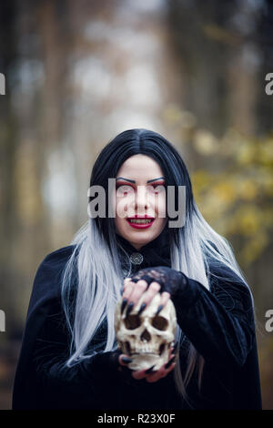 Photo of witch girl in black cloak with skull