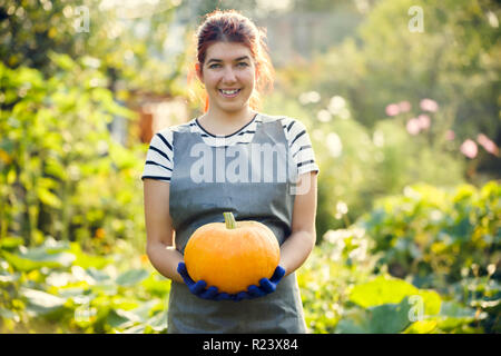 Photo of smiling girl with pumpkin in hands at garden Stock Photo