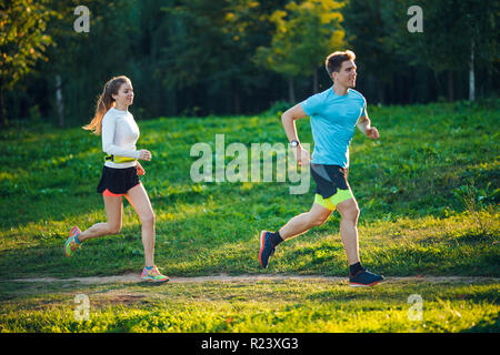 Image of young athletes running in park on summer morning Stock Photo