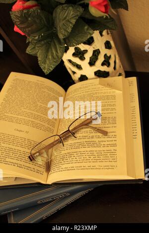 Open dog eared book with glasses Stock Photo