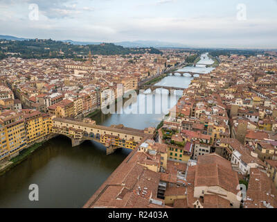 Aerial view of the Ponte Vecchio over the Arno river in Firenze Florence with cloudy sky on a summer morning in Tuscany Italy Stock Photo