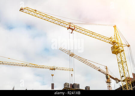 Many cranes and buildings against blue sky. Construction site of hightower structure. Abstract construction industrial background. Stock Photo