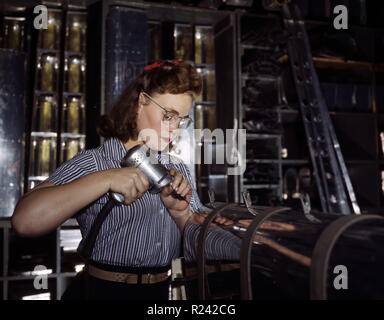 Colour photograph of an female employee operating a hand drill at the North American Aviation Inc. Photographed by Alfred T. Palmer. Dated 1942