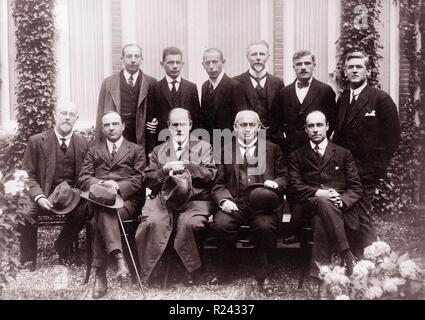 Sigmund Freud with colleagues at the Congress at the Hague. Freud seated (center), Ernest Jones (second from left), Sandor Ferenczi (second from right), and standing (center) Karl Abraham; several unidentified men appear either seated or standing. 1920 Stock Photo