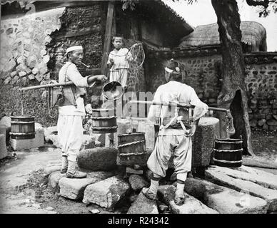 Water carrier visits a village, Korea 1904 Stock Photo