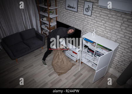 Elevated View Of Thief With Crowbar And Sack Stealing File From Shelf Stock Photo