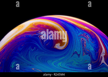 Close up rainbow colours in a soap bubble that look like space or planets or worlds isolated on a black background Stock Photo