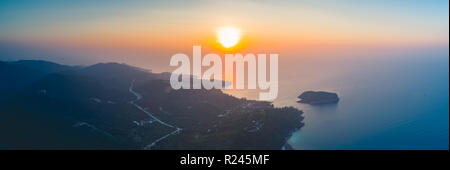 Panorama sunset sky, ocean, island. Aerial drone shot. Thailand. Breathtaking scene the bright sunset over the calm ocean and Ko Pha-ngan island in the Kingdom of Thailand. Perfect spiritual place. Stock Photo