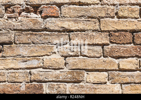 Horizontal photo with texture of wall. Wall was made from bricks with various size. All bricks are worn and some are broken. Color of wall is brown an Stock Photo