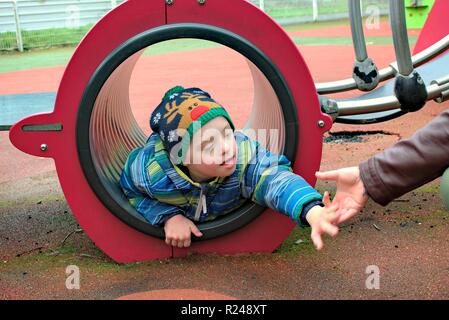 Defect,childcare,medicine and people concept- happy mother and son with down syndrome playing in a playground. Stock Photo
