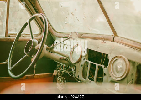 Old photo of Old timer car interior with dusty board and spider web all over the dashboard with rusty levers sepia Stock Photo