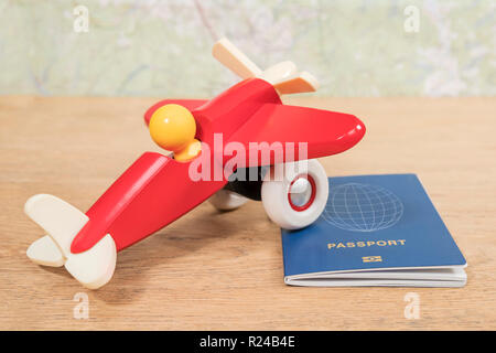 red toy airplane and biometric passport on an old wooden table against a map Stock Photo