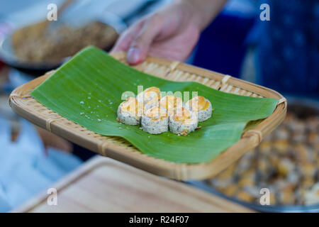 Fresh prepared cashew nuts cakes on banana leaf tray on local market in Bangkok. Traditional thai cuisine made of fresh ingredients. Stock Photo