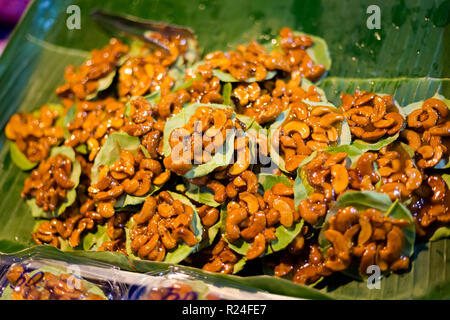 Fresh prepared cashew nuts cakes on banana leaf on local market in Krabi. Traditional thai cuisine made of fresh ingredients. Stock Photo