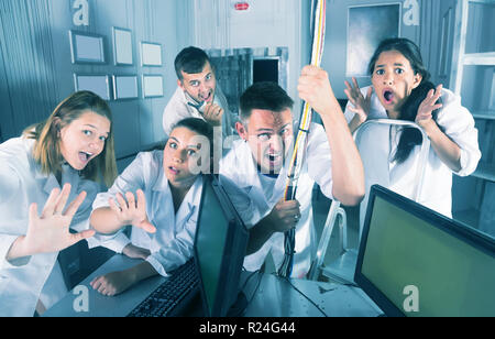 Guys and girls having fun in escape room stylized under abandoned lab Stock Photo
