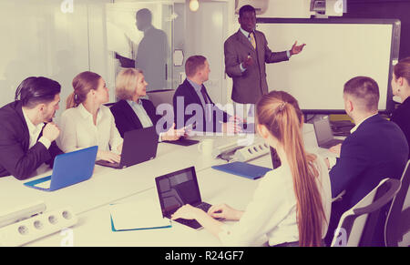 African American young man giving presentation to colleagues at international business meeting Stock Photo