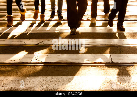 Blurry zebra crossing with silhouettes and shadows of people walking in the cold and sunny autumn Stock Photo