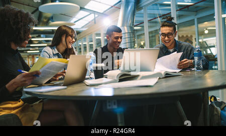 Happy young university students studying with books and laptops in library. Group of multiracial people in college library. Stock Photo