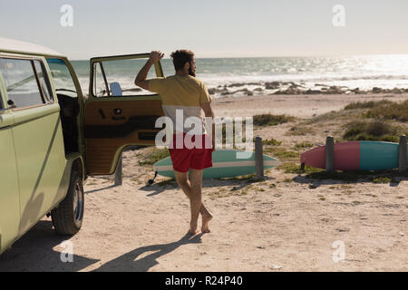 Man leaning on van door near beach Stock Photo