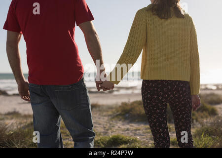 Couple holding hands and standing on beach Stock Photo