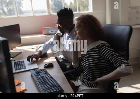 Executives discussing over laptop at desk Stock Photo