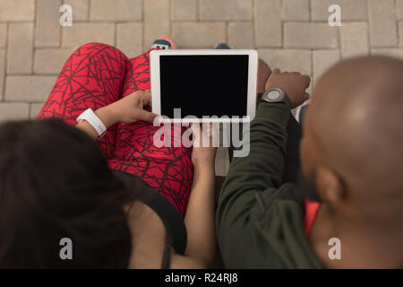 Couple using digital tablet on promenade bench Stock Photo