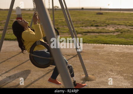 Disabled woman playing on playground swing Stock Photo