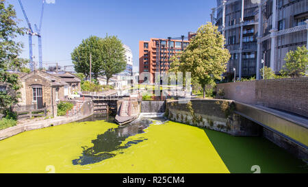 London, England, UK - June 26, 2018: Cyclists and pedestrians pass St Pancras Lock on the Regent's Canal towpath at Gasholders Park in the King's Cros Stock Photo