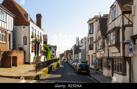 Hastings, England, UK - June 8, 2013: A pedestrian walks past traditional timbered houses, shops and pubs on a narrow street in the Old Town of Hastin Stock Photo