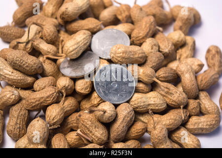 Close up of Peanuts or Groundnuts with indian coins on isolated background. Stock Photo